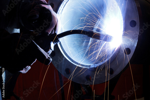 worker weld metal in factory and sparks
