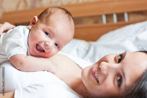 a smiling little child lying on the mother's breast