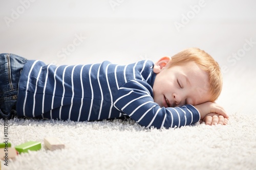 3 year old falling asleep on floor at home photo