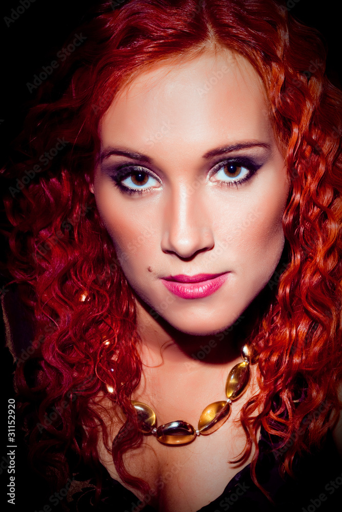Fototapeta premium girl with red curly hair wearing amber necklace on black