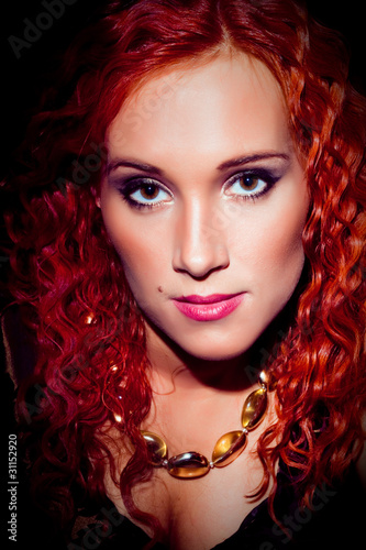Fototapeta Naklejka Na Ścianę i Meble -  girl with red curly hair wearing amber necklace on black