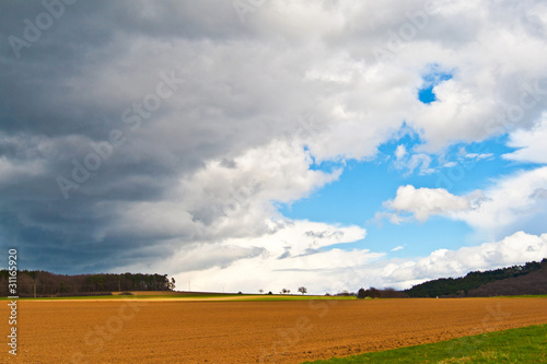 dark clouds and blue sky over fields