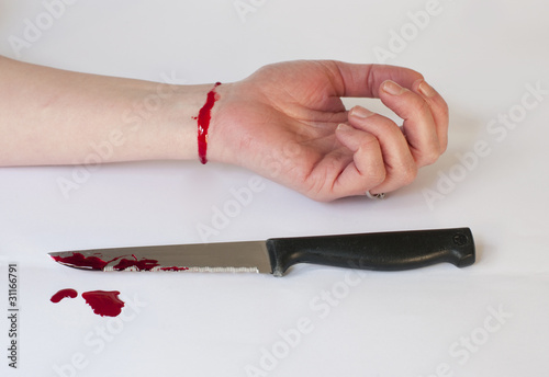 A suicidal womans wrist with blooded knife after suicide attempt