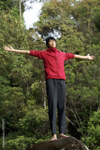 Asian man with outstretched arms at peace with nature outdoors