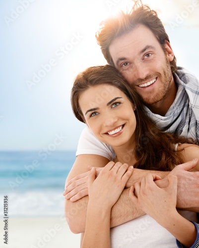 Happy young couple embracing on summer beach