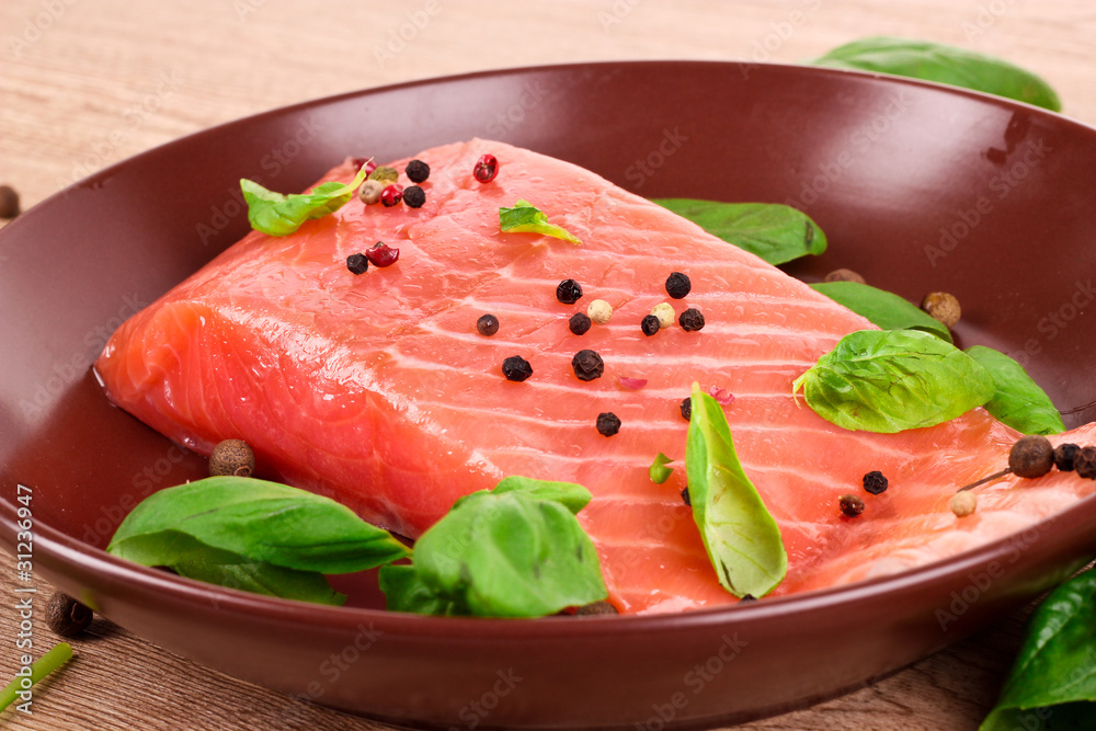 Red fish on the plate with pepper and green leaves