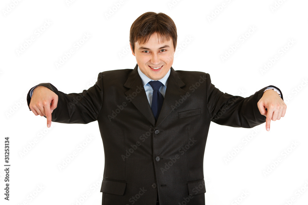 Smiling young businessman pointing down isolated on white. Smiling young businessman pointing down isolated on white.
