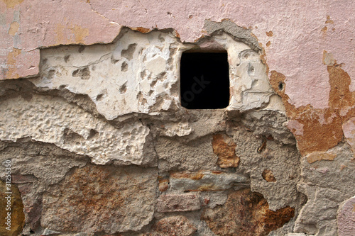 old crumbling wall texture with a small window hole