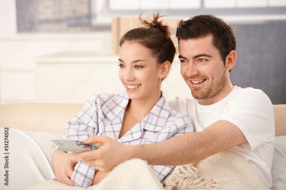 Happy couple watching television in bed Happy couple watching television in bed