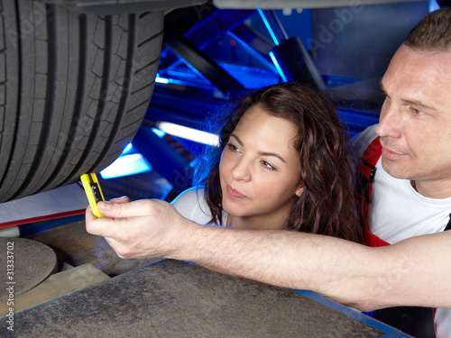 Motormechanic and customer checking the tread depth of a tyre photo