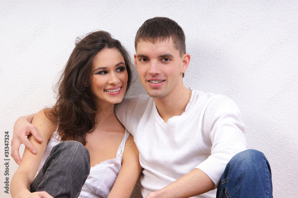 A beautiful couple of two young lovers on a light background A beautiful couple of two young lovers on a light background