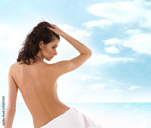 Back of a young and fit Caucasian brunette woman in a towel © Acronym