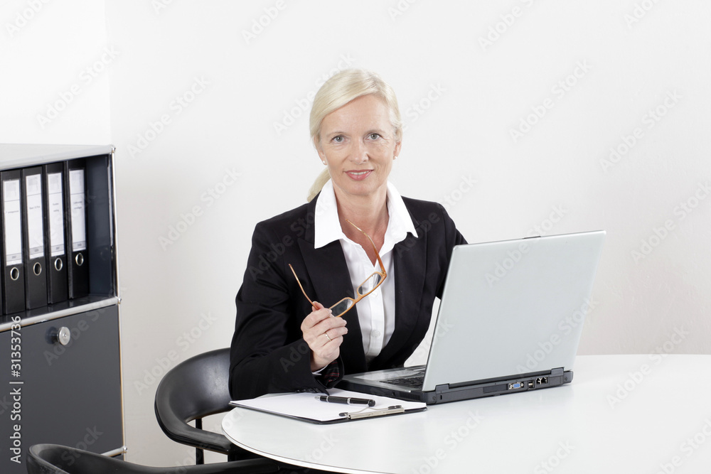 Frau am Schreibtisch mit Laptop freundlich Frau am Schreibtisch mit Laptop freundlich