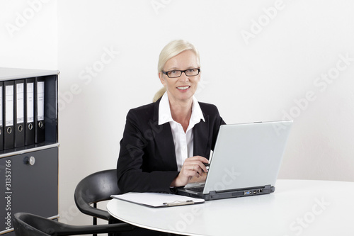 Frau am Schreibtisch mit Laptop lachend