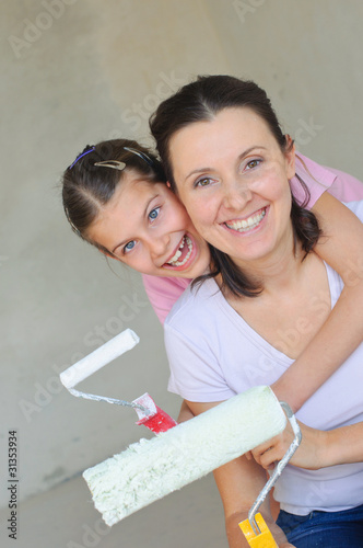 Mother and douther painting a wall with roller photo