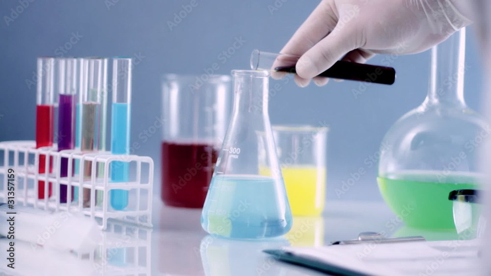 Scientist mixing chemicals in Erlenmeyer flask writing results Scientist mixing chemicals in Erlenmeyer flask writing results