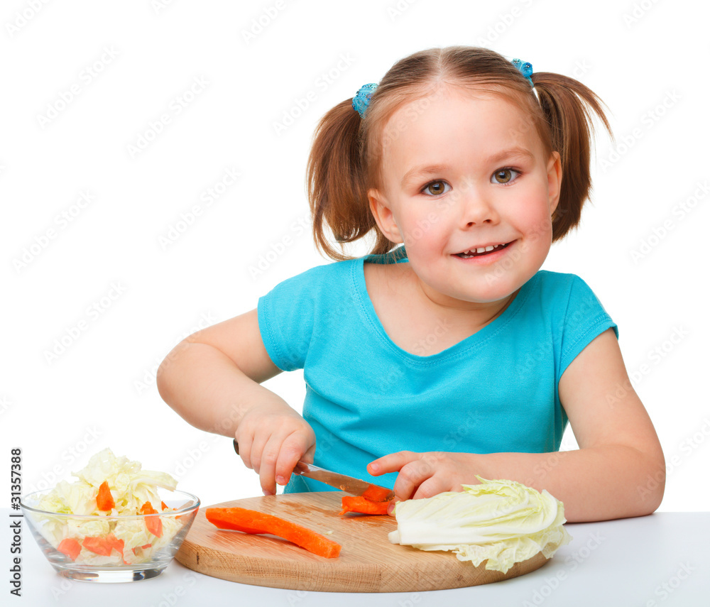 Little girl is cutting carrot for salad Little girl is cutting carrot for salad