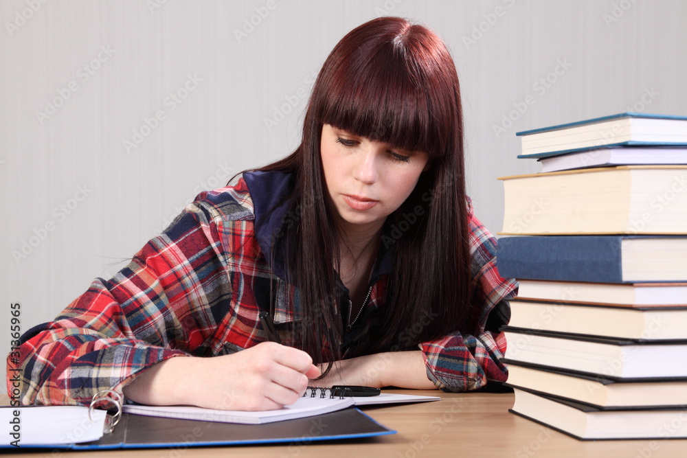 Young student girl doing homework writing in book Young student girl doing homework writing in book