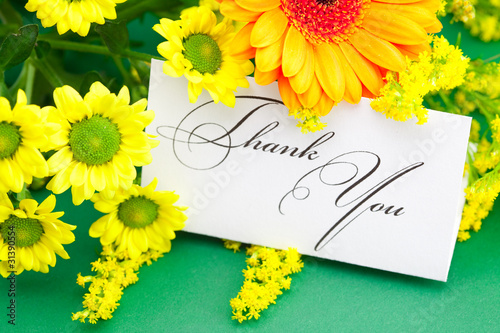 yellow daisy,gerbera and card signed thank you on green backgrou