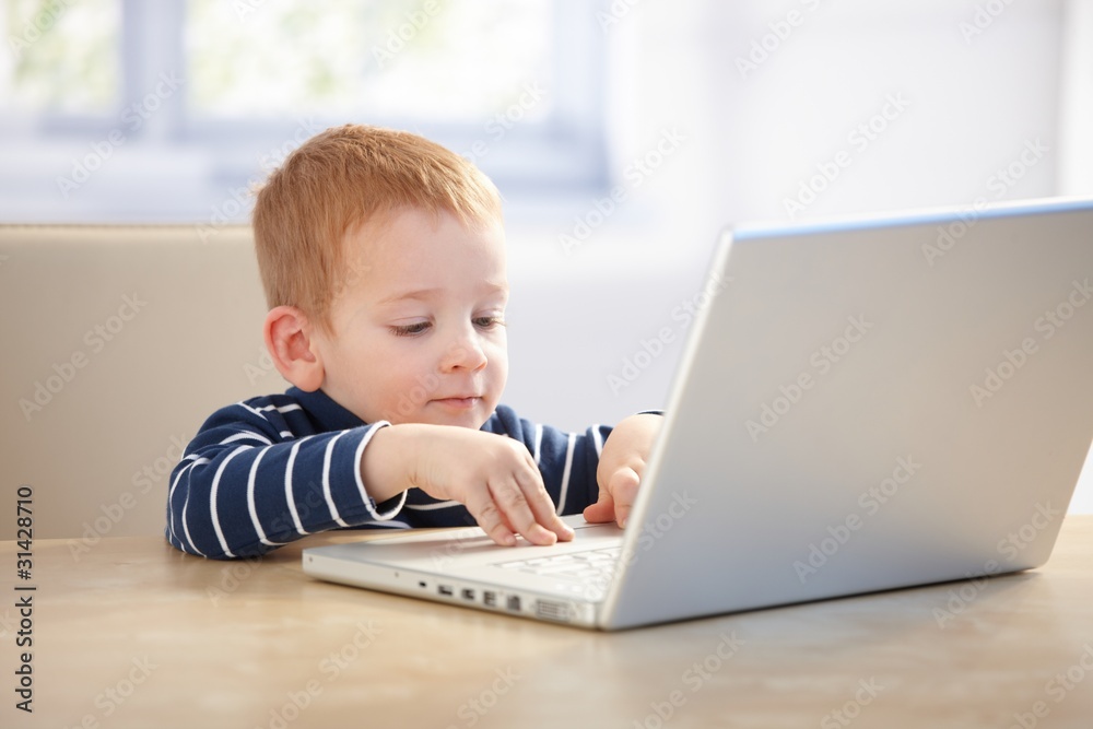 Little businessman using laptop at home