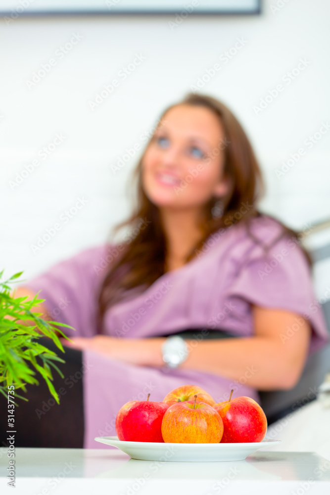 Fruit platter on table and woman sitting on sofa in background. Fruit platter on table and woman sitting on sofa in background.