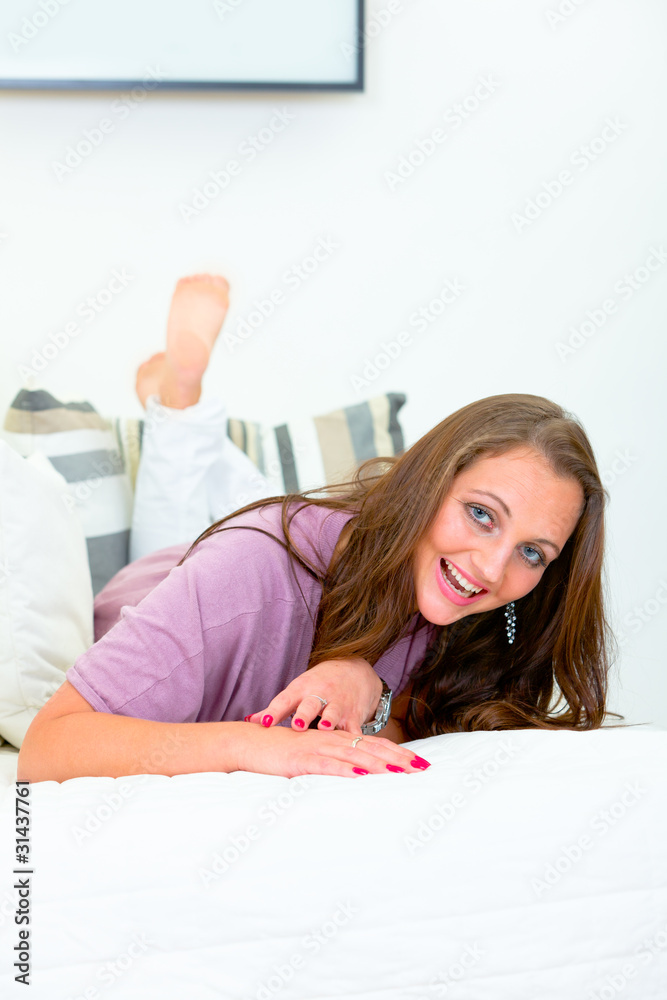 Laughing attractive woman lying on white sofa at home. Laughing attractive woman lying on white sofa at home.