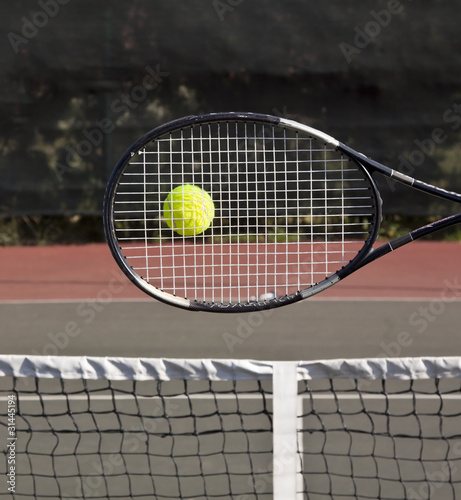 Racquet with tennis ball on court hit