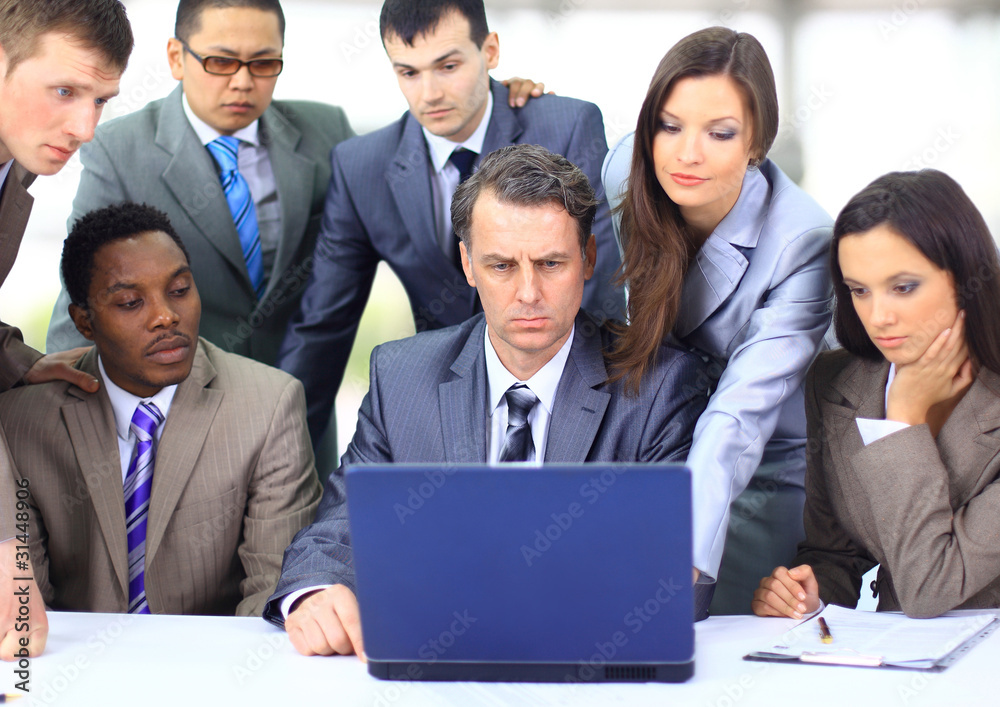 Interracial business team working at laptop in a modern Interracial business team working at laptop in a modern