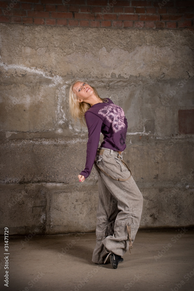 Beautiful hip hop girl dancing over grey brick wall
