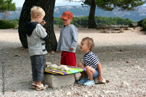 Tree boys play with stones as goods, play market outside
