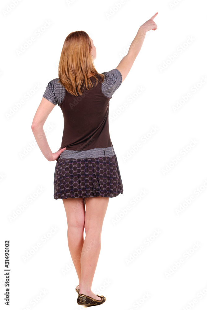 Beautiful young woman in dress pointing at wall. Rear view. Beautiful young woman in dress pointing at wall. Rear view.