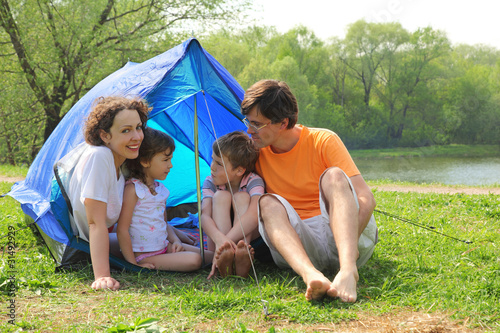 Happy family with two children sitting in tent