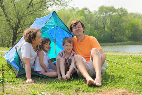 Happy family with two children sitting in tent