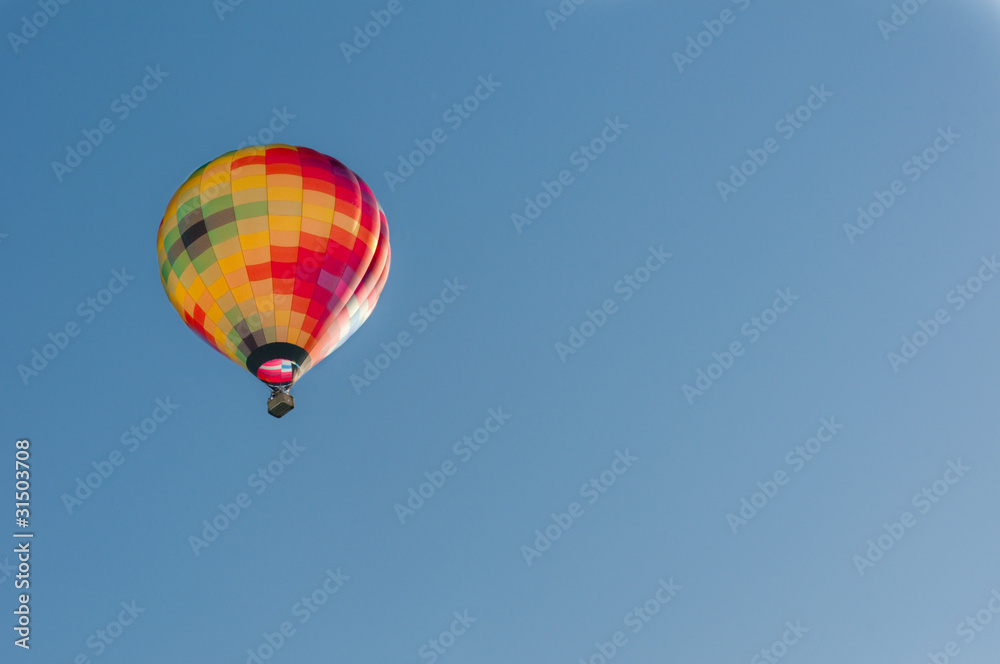 Hot air balloon rising serenely into an early morning blue sky. Hot air balloon rising serenely into an early morning blue sky.