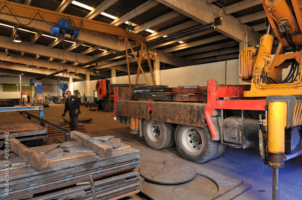 Crane loading truck at metal factory.