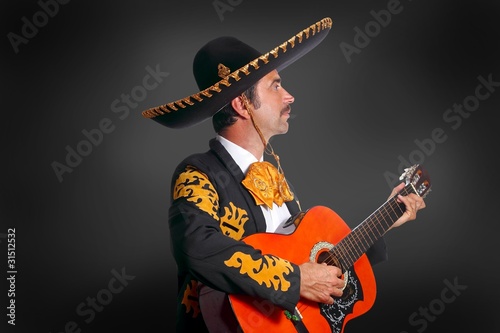 Charro Mariachi playing guitar on black