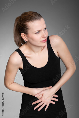 Young woman with stomach issues on grey