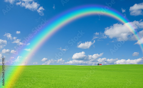 Green grass and red roof house and rainbow