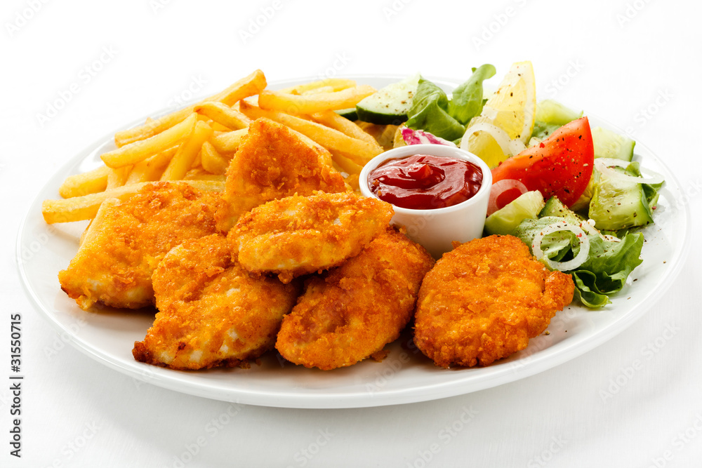Fried chicken nuggets, French fries and vegetables Fried chicken nuggets, French fries and vegetables