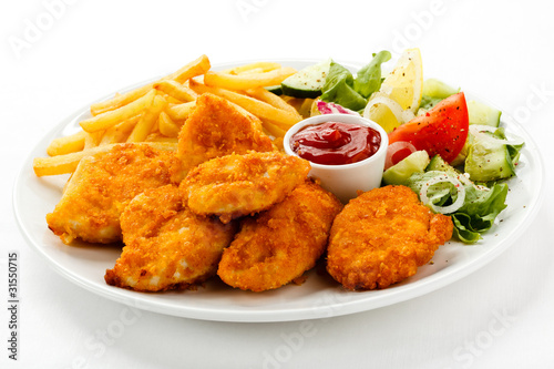 Fried chicken nuggets, French fries and vegetables photo