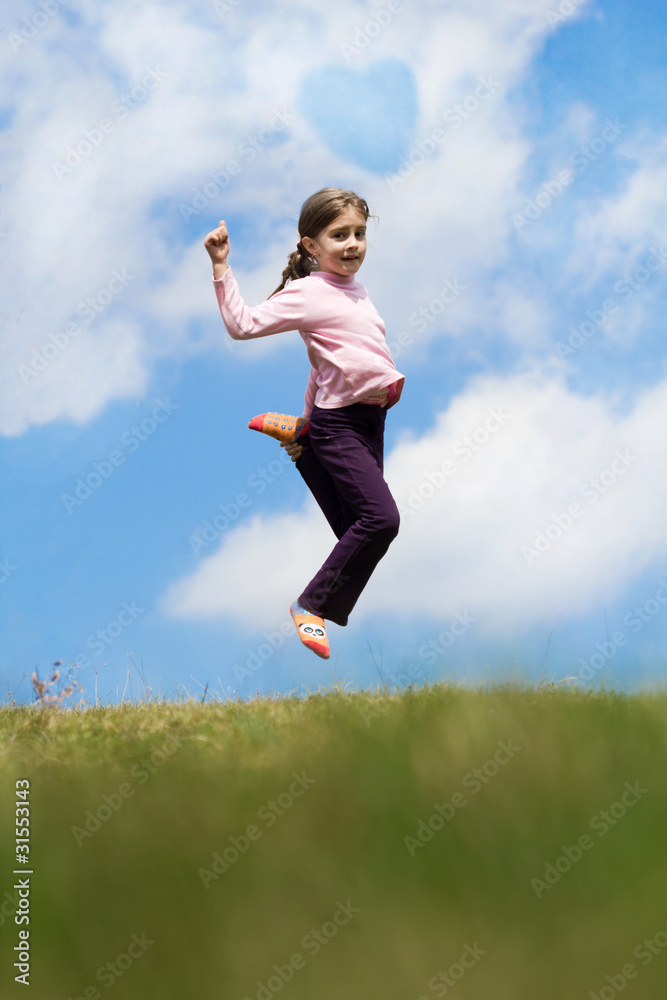 Girl jumping on the meadow, with blue sky and clouds in backgrou Girl jumping on the meadow, with blue sky and clouds in backgrou