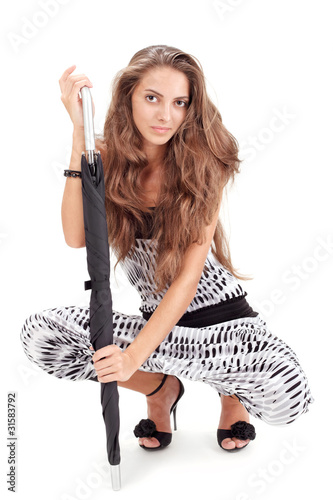 Young pretty lady in harem pants posing with black umbrella on w