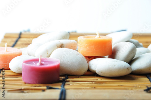 Three candles and stones on bamboo mat, and isolated white backg