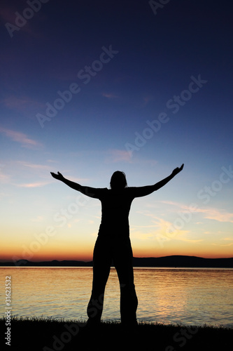 Young woman silhouette raised hands standing at coast © Zsolt Biczó
