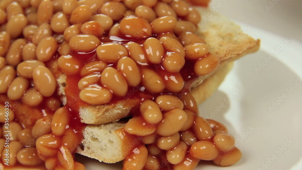 Hot baked beans poured and cascading over crisp toast. Hot baked beans poured and cascading over crisp toast.