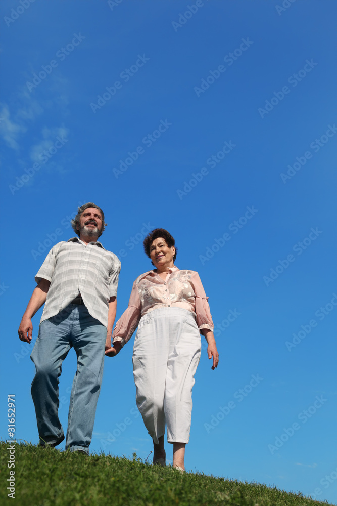 old man and woman standing on hill and holding for hand