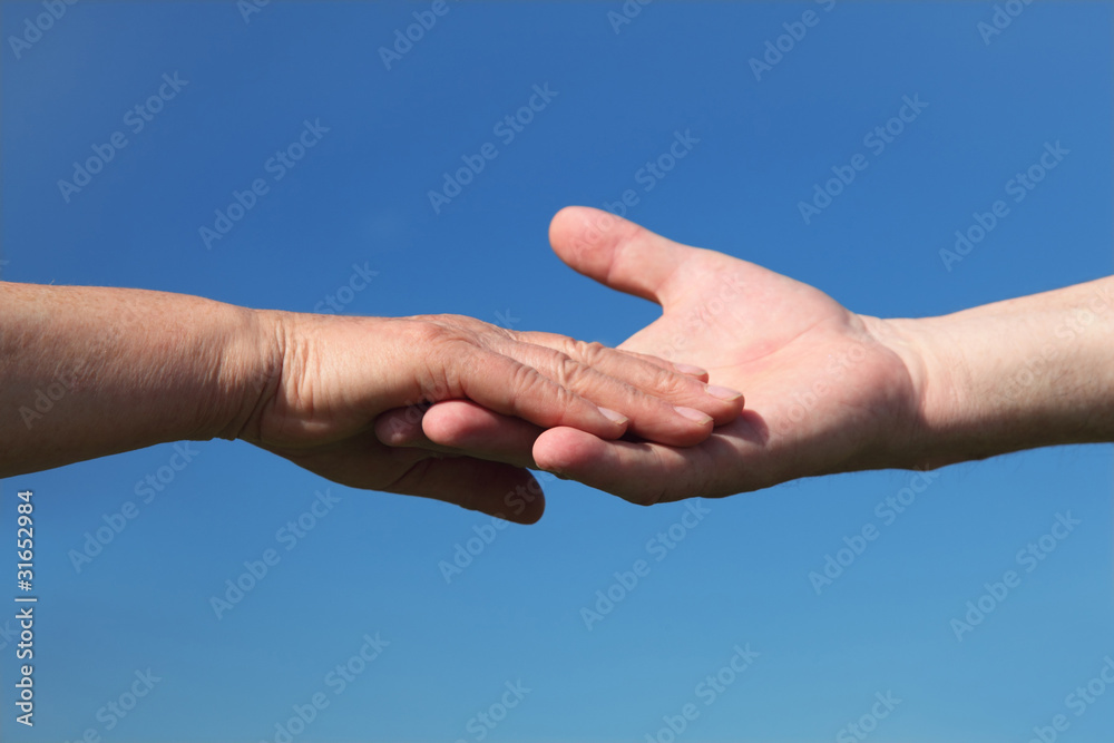 closeup of old people holding for hands, blue sky