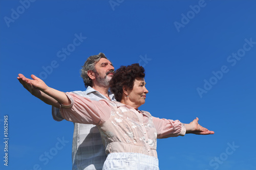 old man and woman standing, smiling and looking at side