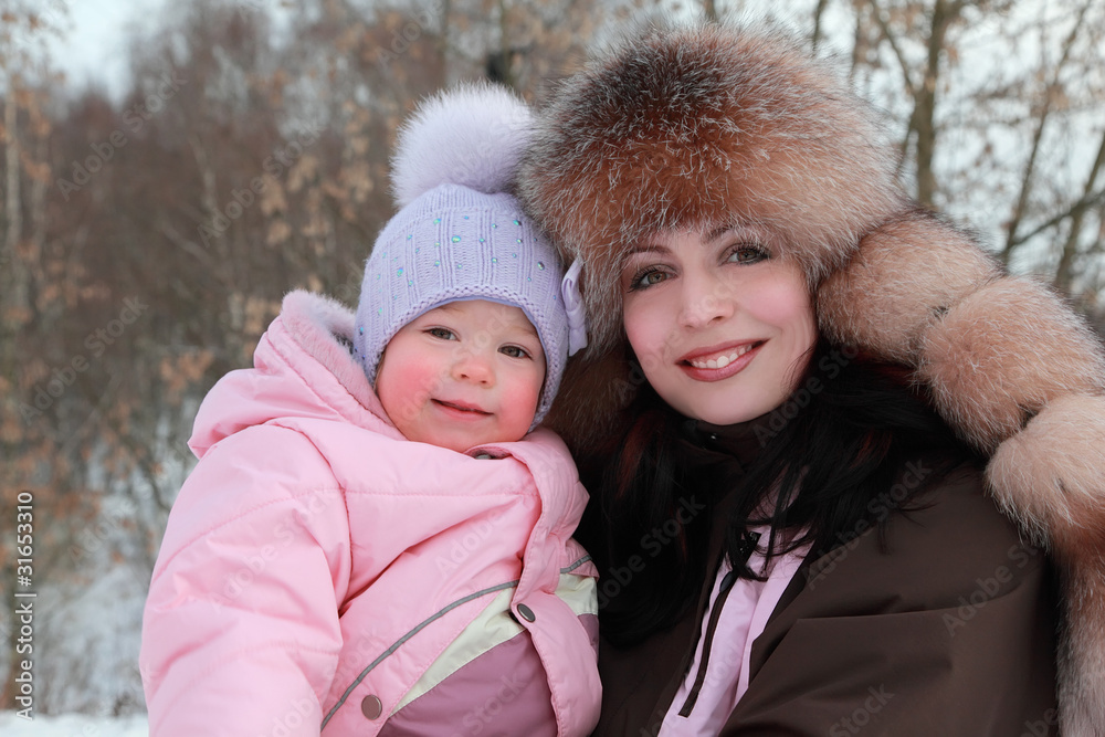 mother hugs little daughter at winter, focus on woman