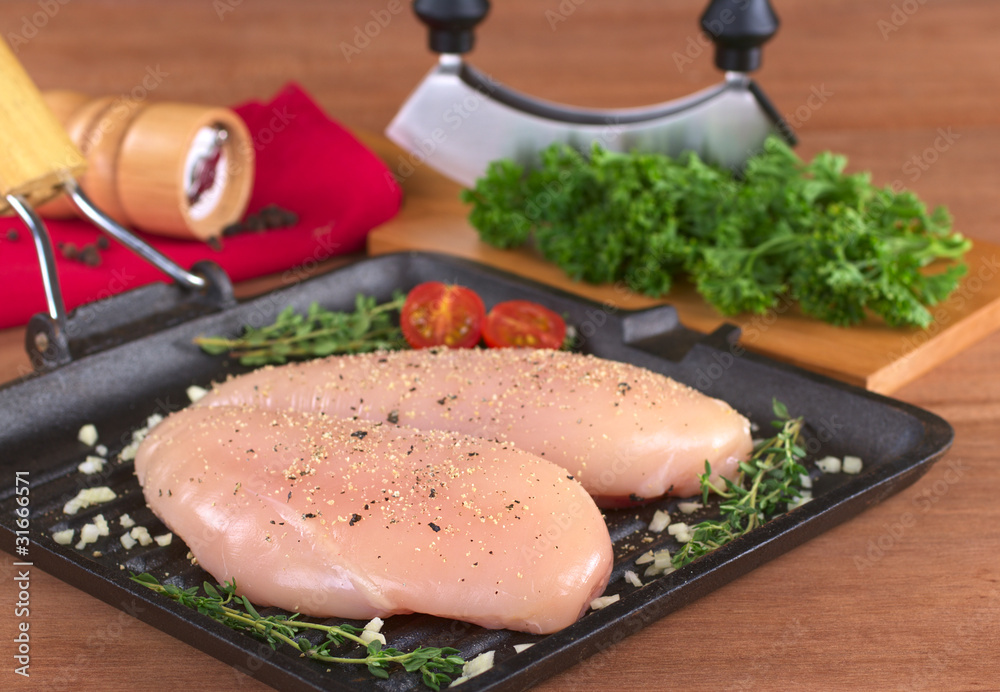 Raw chicken breast with seasoning in frying pan Raw chicken breast with seasoning in frying pan